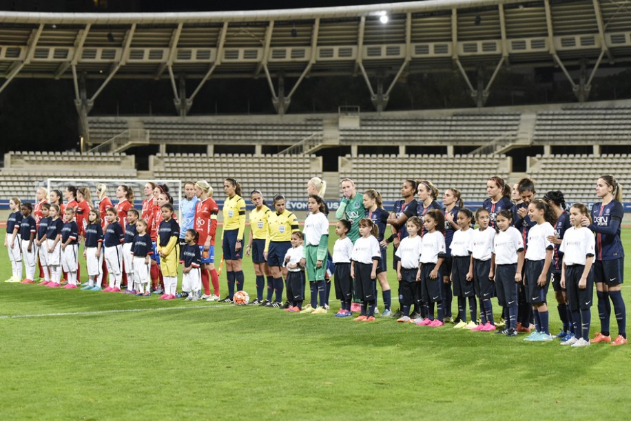 Los equipos del Paris Saint-Germain (derecha) y el Örebro de Suecia, junto al cuerpo arbitral de Portugal, saludan al público que, en baja cantidad, asistió al estadio Charléty, de París, Francia (foto 'Team Pics/PSG').