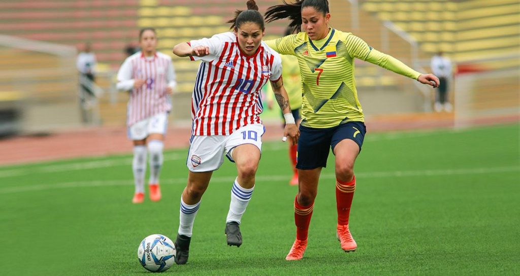 Paraguay y Colombia igualaron sin goles en la jornada de apertura del Grupo A, del fútbol femenino de los Juegos Panamericanos, el 28 de julio en Lima, Perú. La guaraní Jessica Martínez (Nº 10) y la cafetera Marcela Restrepo pelean el balón en el mediocampo (foto sitio "Lima 2019").