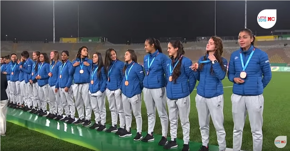 
Las seleccionadas de Costa Rica lucen orgullosas su medalla de bronce al obtener el tercer puesto, en el fútbol femenino de los Juegos Panamericanos de Lima 2019 (Imagen capturada de la transmisión oficial de 'Marca Claro' por YouTube).